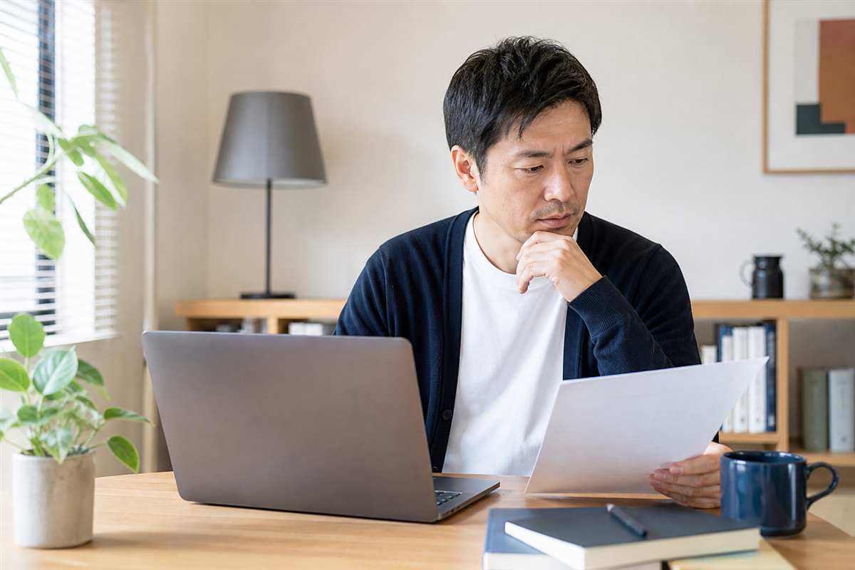 AIの出力と紙のメモを照らし合わせて内容を確認する40代の会社員
