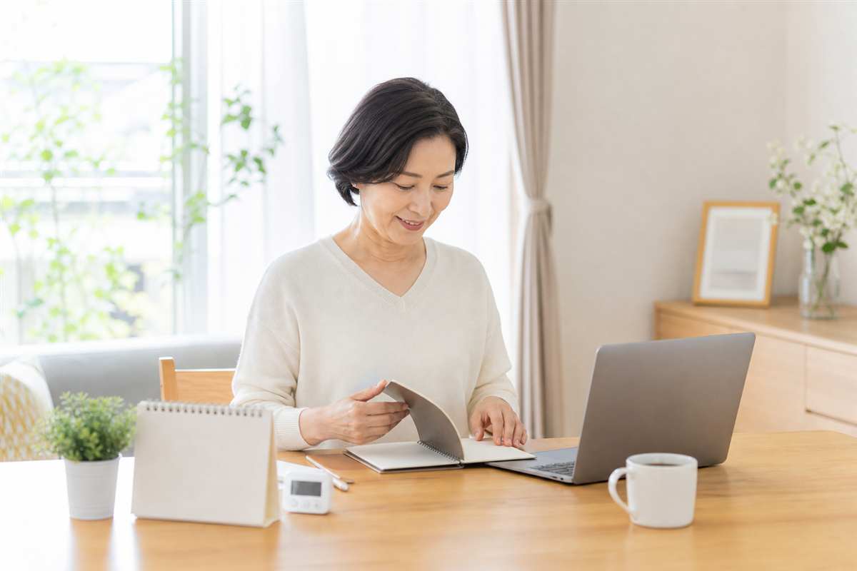朝の机でノートを開き、小さな学習を再開する50代の女性